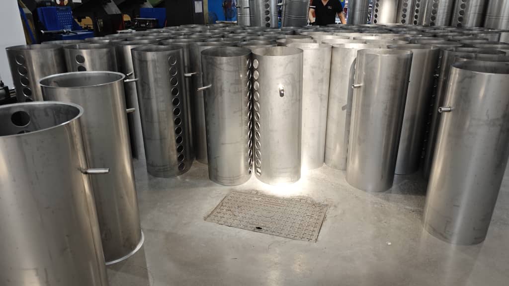 Calentadores Solares al por Mayor para Constructoras y Gobierno 3 Varios tanques exteriores de calentadores solares de agua, hechos de acero inoxidable, apilados en el área de producción de una fábrica. Los tanques tienen múltiples orificios para insertar los tubos de vacío.